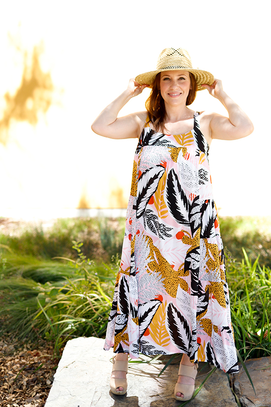 Woman stands in front of greenery wearing a midi length Marcel dress