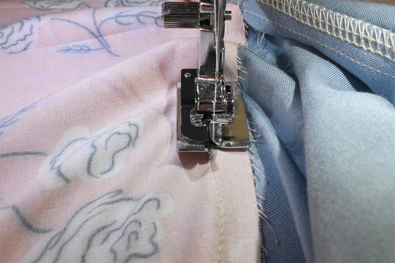 A machine presser foot is shown stitching closely to the seam.