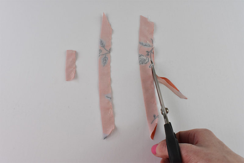 Scissors are shown trimming the seam allowance of sewn strap pieces. 