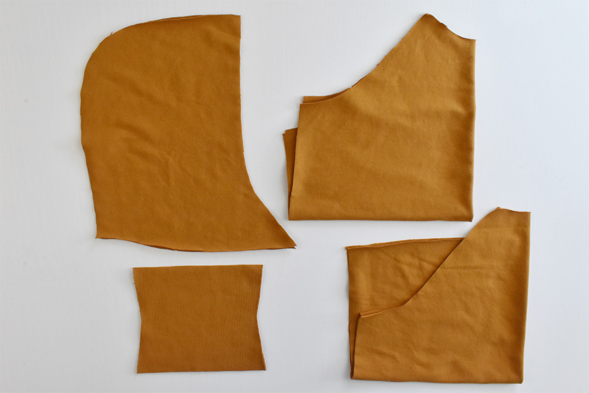 Gold colored fabric is cut into pieces for a page hoodie. 