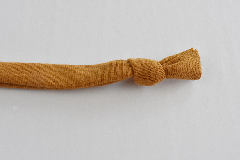 A knit fabric tube is shown right side out and knotted