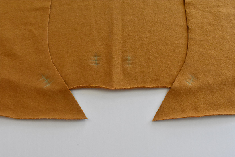 Golden color fabric pieces are shown with chalk markings indicating buttonhole/grommet placement. 