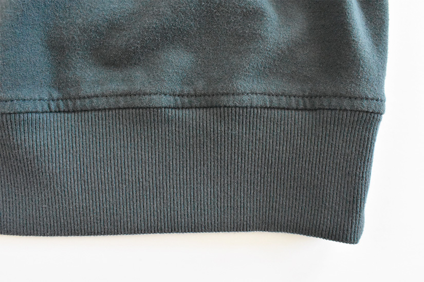 Close up of topstitching on blue/green fabric hem band. 