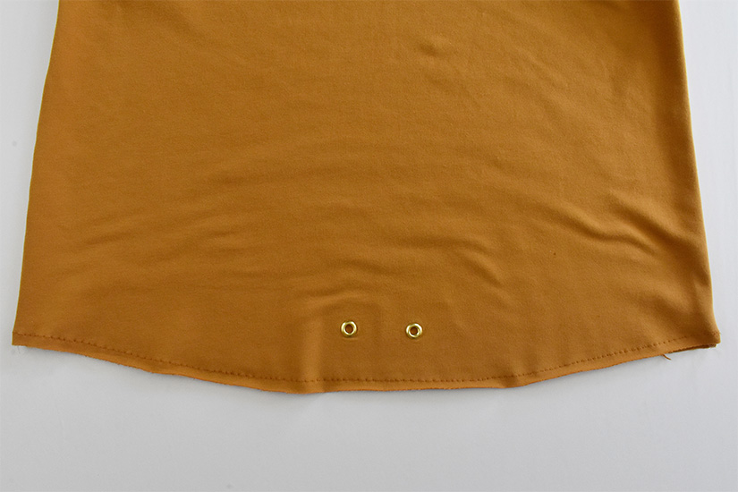 A close up of stitching on the bottom of a gold hoodie bodice