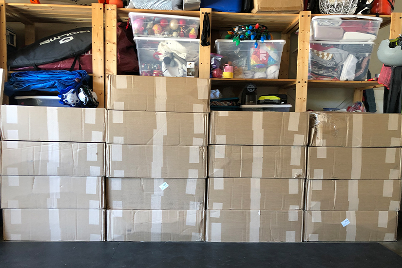 17 large cardboard boxes containing patterns are stacked in a garage. 