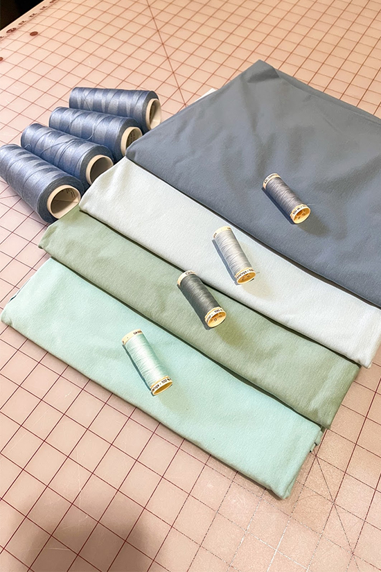 Four blue colored fabrics are shown laying on a cutting mat.