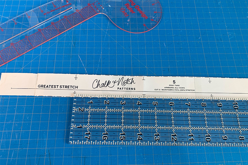A ruler and armband pattern piece lays on a blue cutting mat.