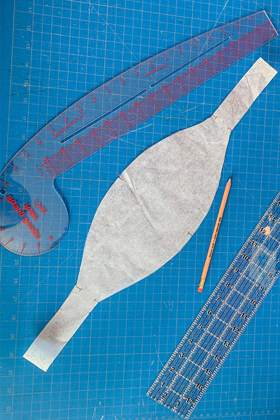 The newly traced ruffle band pattern piece is shown on a blue cutting mat. 