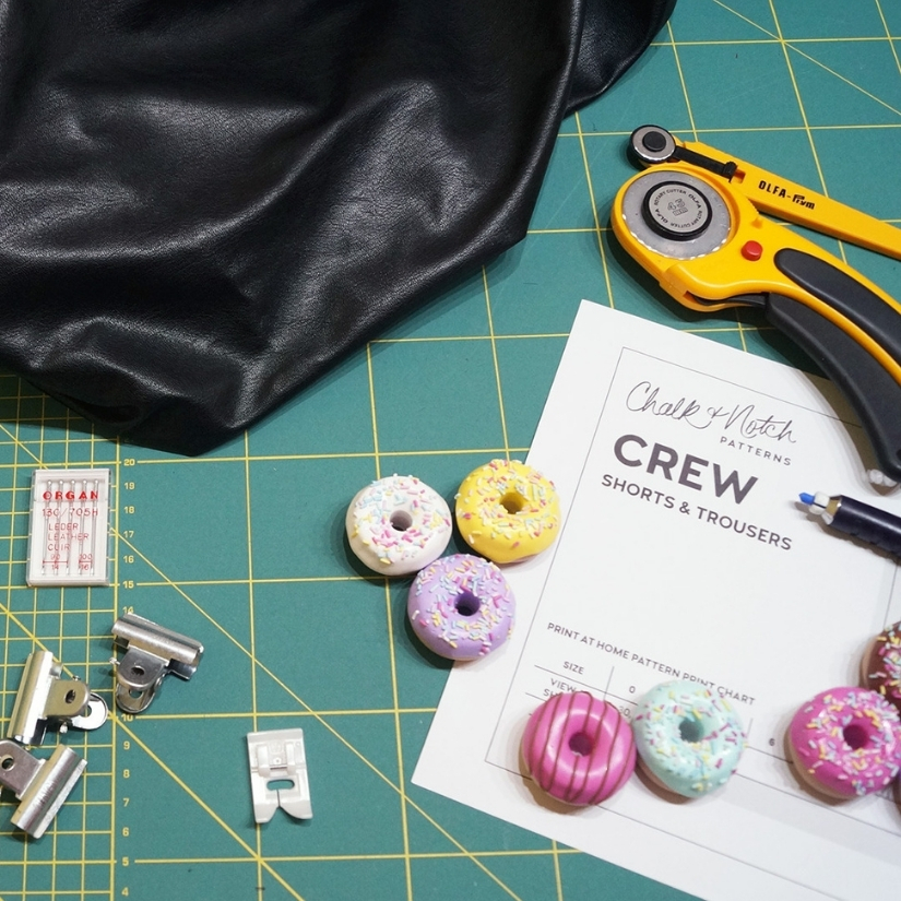 Black faux leather and various sewing tools on a green cutting mat.