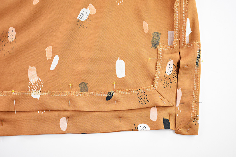 The hem of the Farrah sewing pattern is shown pinned.