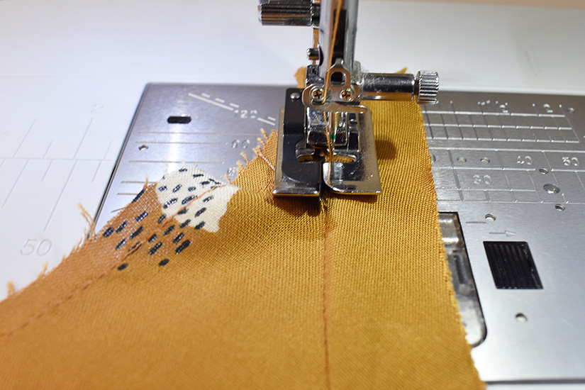 A sewing machine is shown understitching the bias of the Farrah sewing pattern armhole.