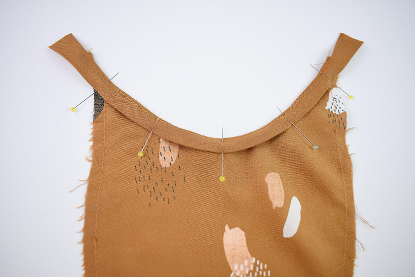 The armhole bias of the Farrah sewing pattern is shown pinned to the top of the armhole gusset.