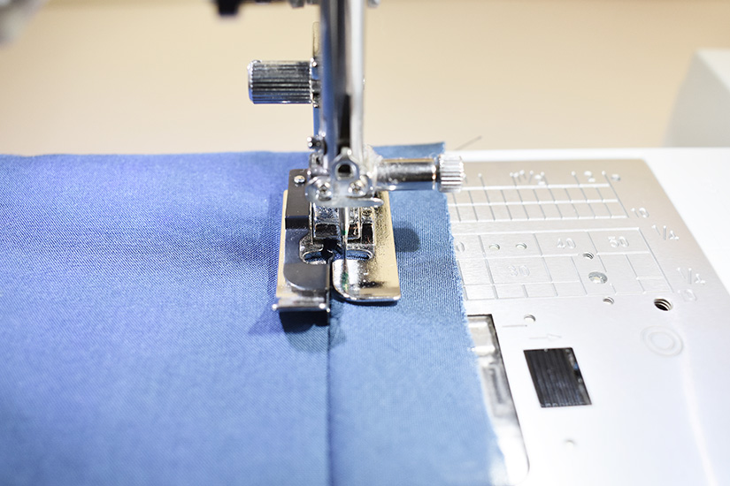 A sewing machine foot is shown understitching the Farrah armhole bias tape. 