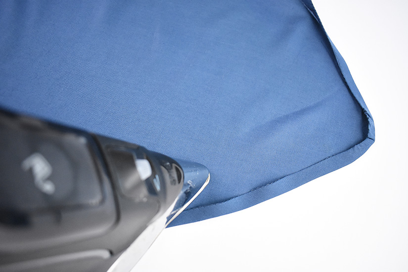 An iron presses blue fabric