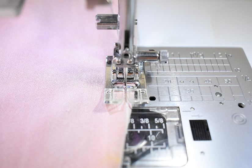 A sewing machine is shown sewing the ends of a dart. 