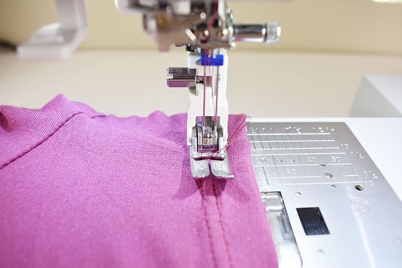 A sewing machine with double needle stitches a hem.