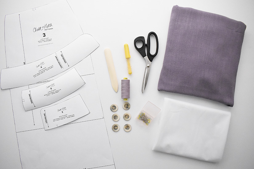 Paper pattern pieces, fabric, and various notions for the Evelyn Skirt sewing pattern are shown on a white background.