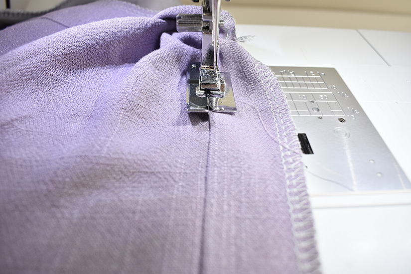 A sewing machine understitches along the edge of a seam. 