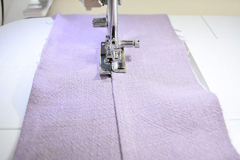 A sewing machine understitches the waistband. 