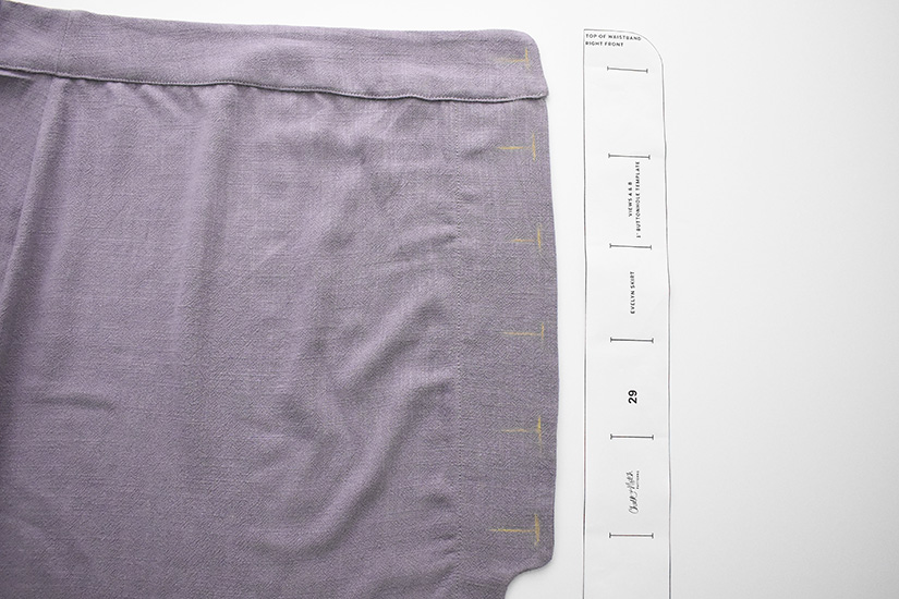 The buttonhole guide is shown next to markings on the front skirt. 