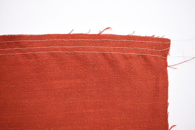 Three lines of stitching are shown on orange fabric. 