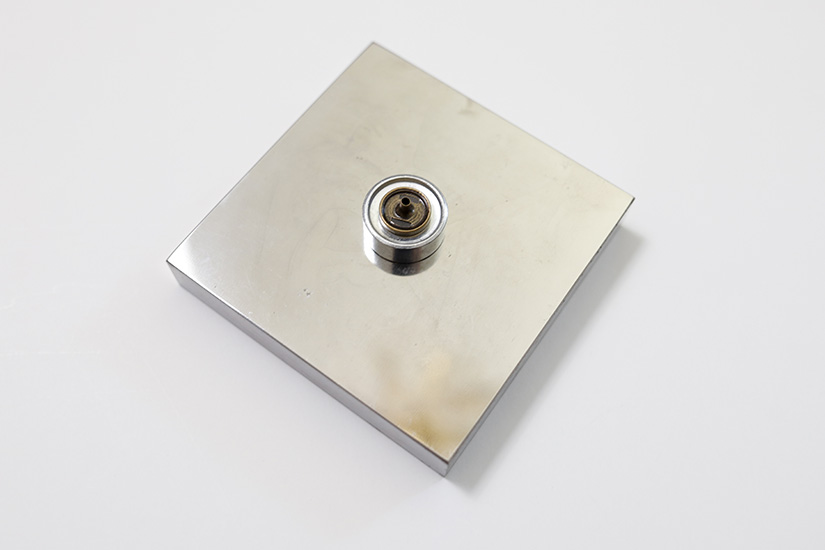A snap and setting tool are shown sitting on a hard metal surface. 