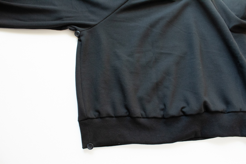 Buttons are sewn to the corners of the bat costume sweatshirt.