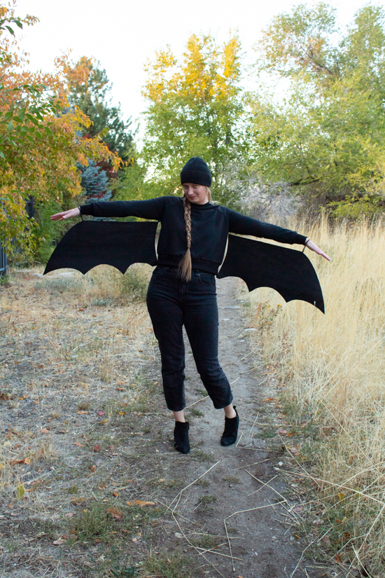 A woman stands wearing a DIY bat Halloween costume. 