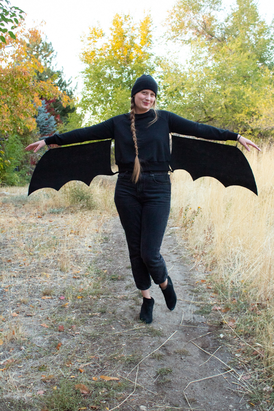 Nicole stands with arms extended showing off her DIY halloween bat costume. 