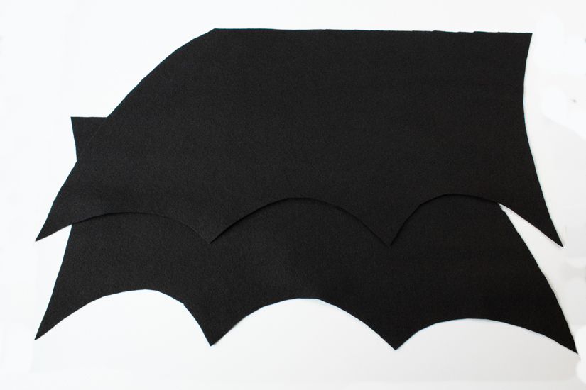 Two Halloween costume felt bat wing pieces lay on a white background.