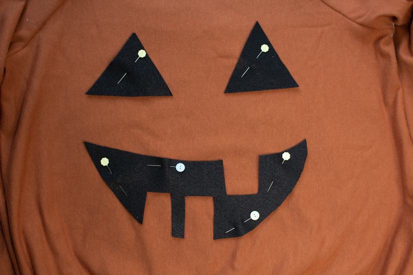  A Jack o' lantern face is pinned to the front of a sweatshirt to make a DIY Halloween Costume